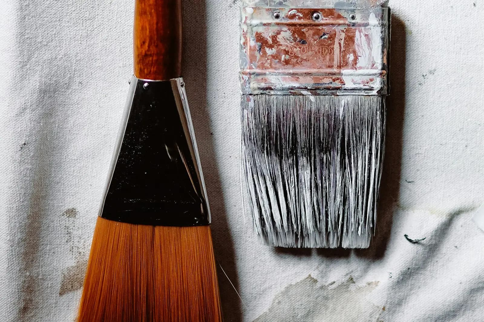 Two well-used decorating brushes on a dust sheet