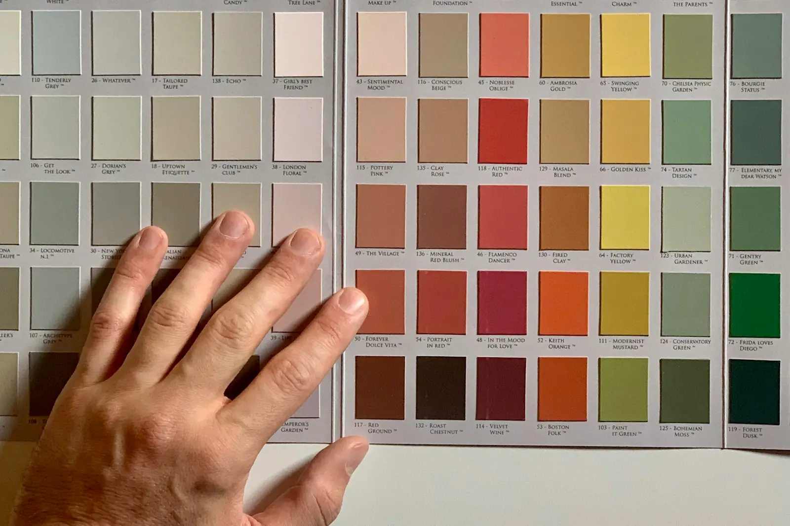 Hand resting on a wall of paint colour sample cards