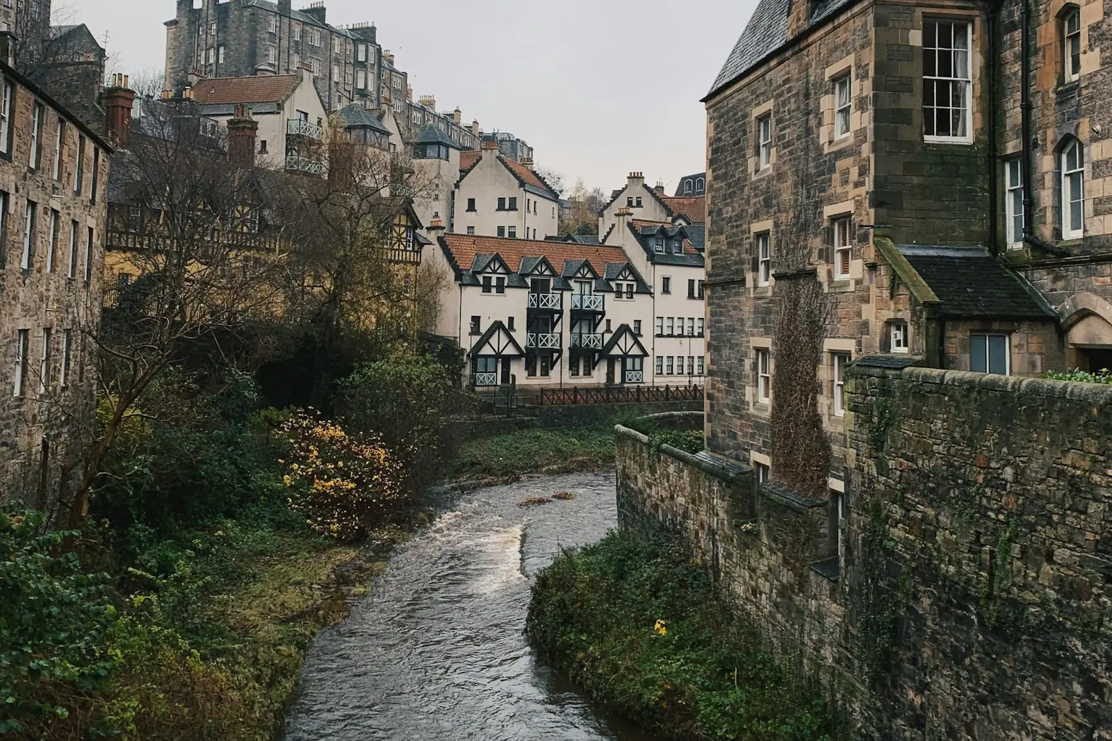 Stone tenement buildings beside a river in a Scottish city