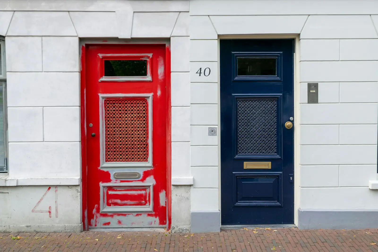 Red and navy painted front doors on a white stucco terrace