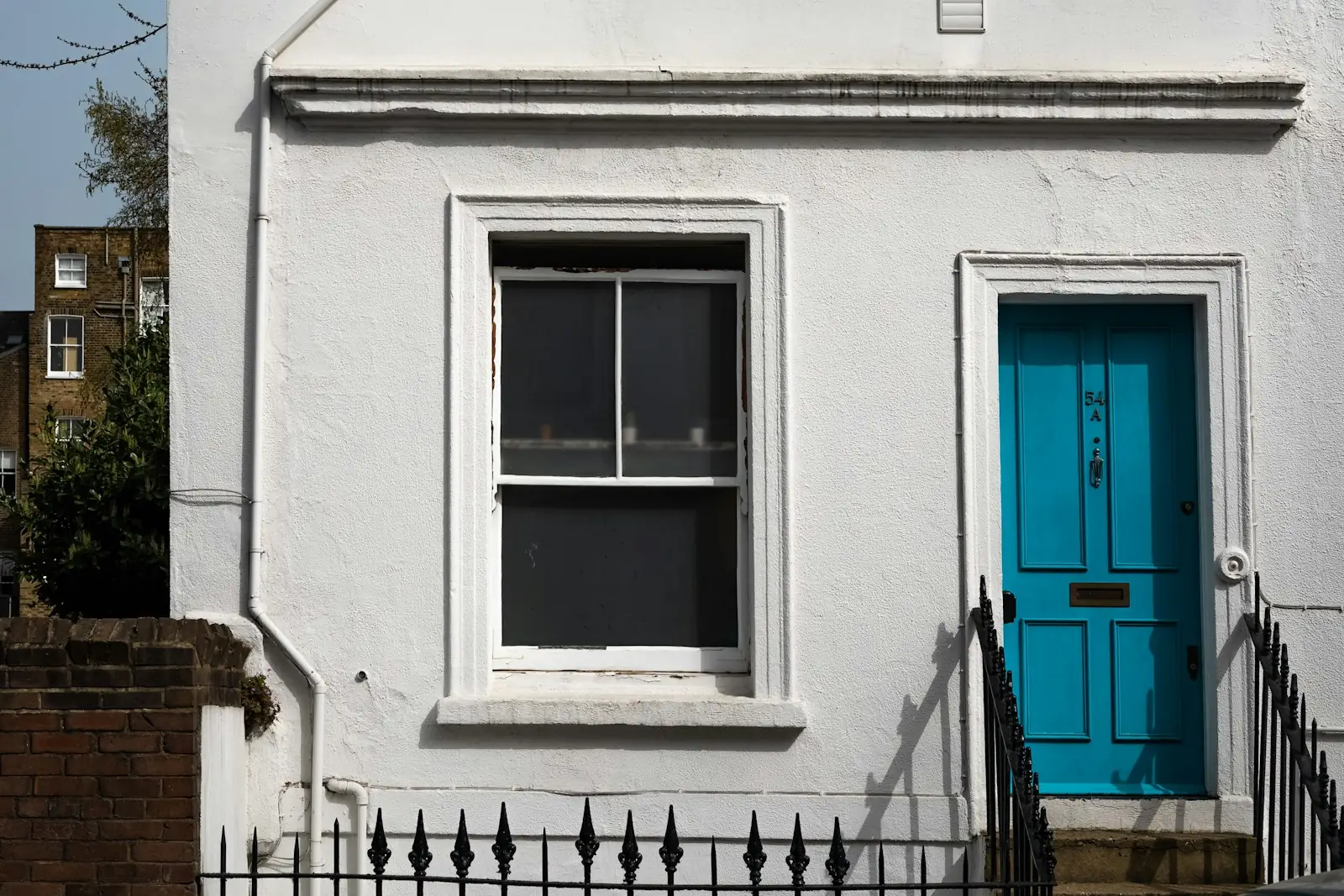 White painted render on a house with a teal front door