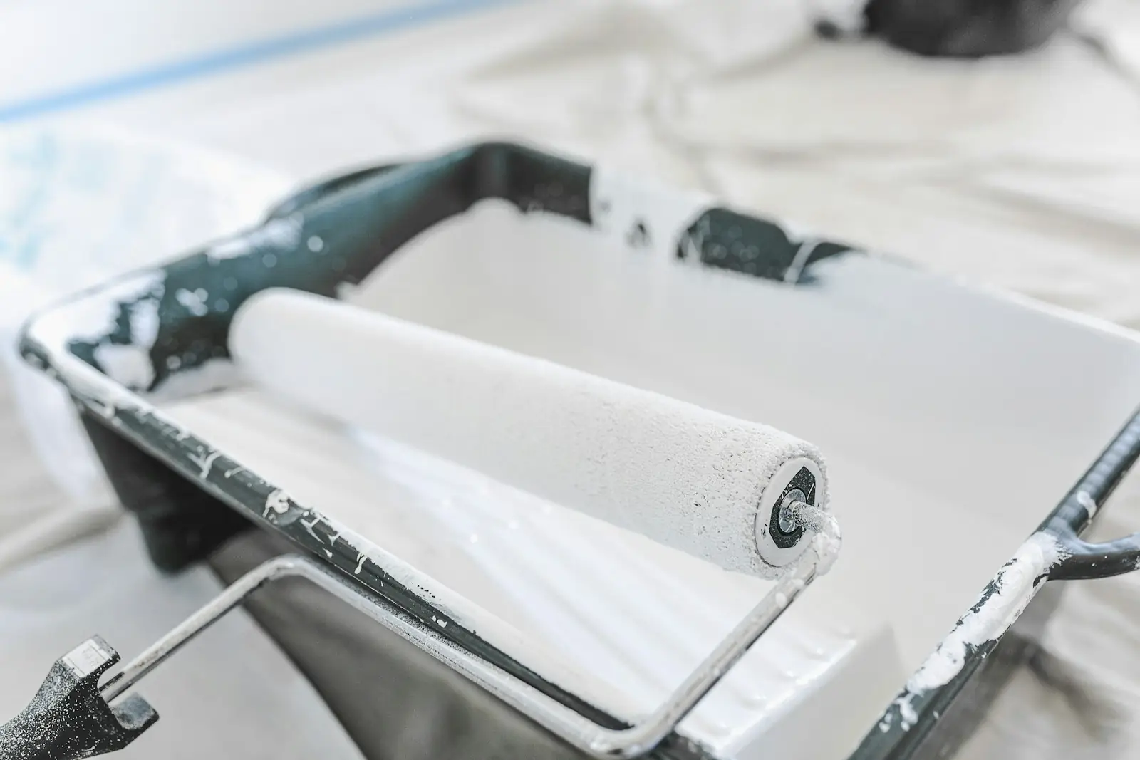 Paint roller resting in a tray on a dust sheet
